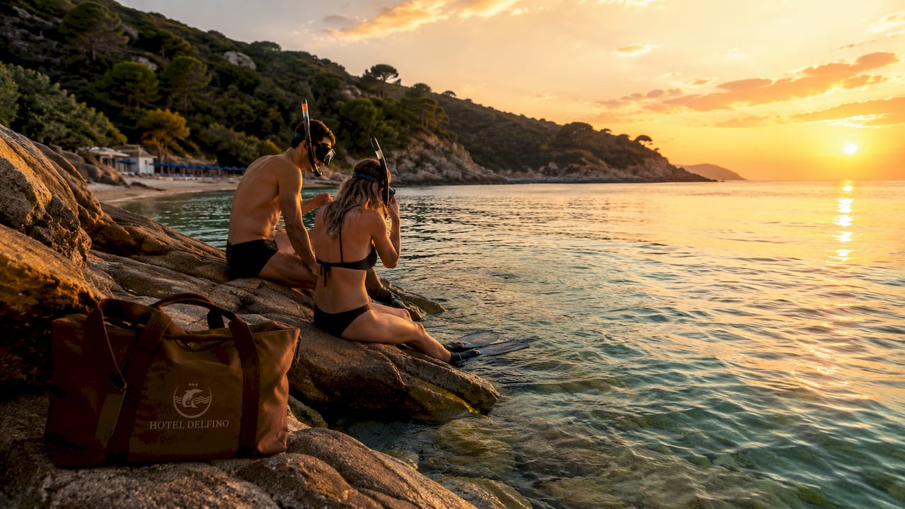 Appassionati di snorkeling si preparano sulla suggestiva spiaggia dell’Elba, pronti a tuffarsi nelle sue acque cristalline.
